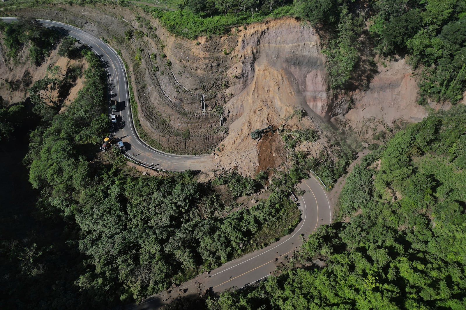 A backhoe works to clear a road blocked by a landslide in Palin, Guatemala, after dozens of earthquakes and aftershocks were recorded in a matter of hours. (AP Photo/Moises Castillo)