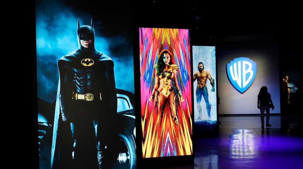 FILE - A visitor walks past portraits of DC Comics superheroes as she enters the "Action and Magic Made Here" interactive experience at the Warner Bros. Studio Tour Hollywood media preview on June 24, 2021, in Burbank, Calif. (AP Photo/Chris Pizzello, File)