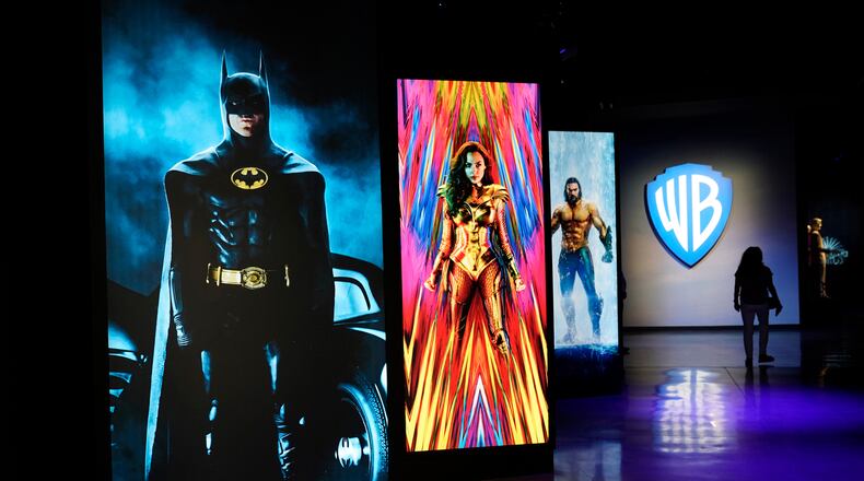 FILE - A visitor walks past portraits of DC Comics superheroes as she enters the "Action and Magic Made Here" interactive experience at the Warner Bros. Studio Tour Hollywood media preview on June 24, 2021, in Burbank, Calif. (AP Photo/Chris Pizzello, File)