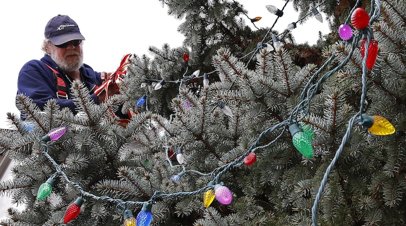 Ron Wright, an employee of the New Carlisle, decorated the city’s Christmas tree at the intersection of North Main Street and Washington Street last year. BILL LACKEY/STAFF