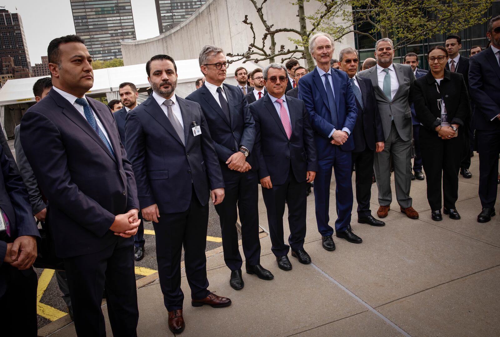 Syria's Foreign Minister Asaad Al-Shibani sands next to Middle East ambassadors as they attend a ceremony where the Syrian flag was added to the 100 flags flying in line at United Nations Headquarters on Friday, April 25, 2025. (AP Photo/Kena Betancur)
