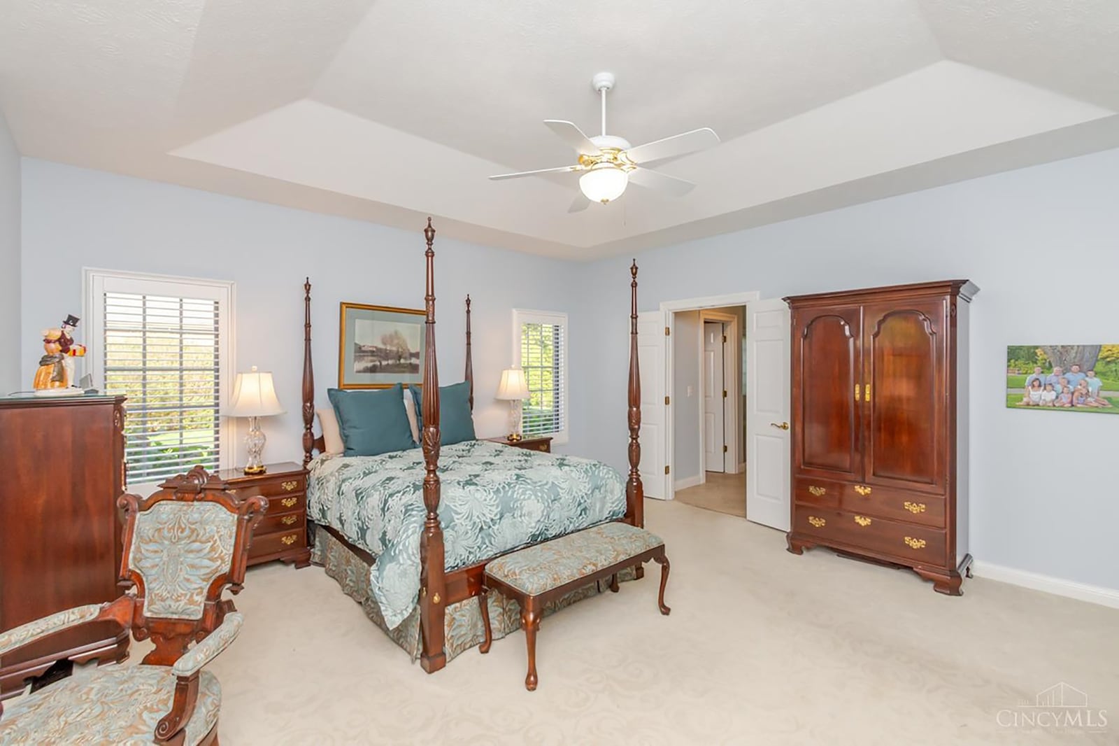 The primary bedroom suite has a tray ceiling with a ceiling fan, neutral carpeting, wood window blinds and an ensuite bathroom and walk in closet with custom organizing system. CONTRIBUTED
