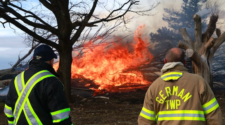 German Township firefighters watch as a house burns Monday, Dec. 23, 2024. The house on Ballentine Pike was deliberately set by the owner to demolish the house. BILL LACKEY/STAFF