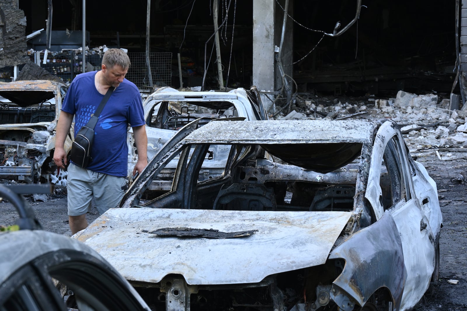 A resident looks at damaged cars at a residential area following Russia's drone attack in Odesa, Ukraine, Tuesday, July 22, 2025. (AP Photo/Michael Shtekel)