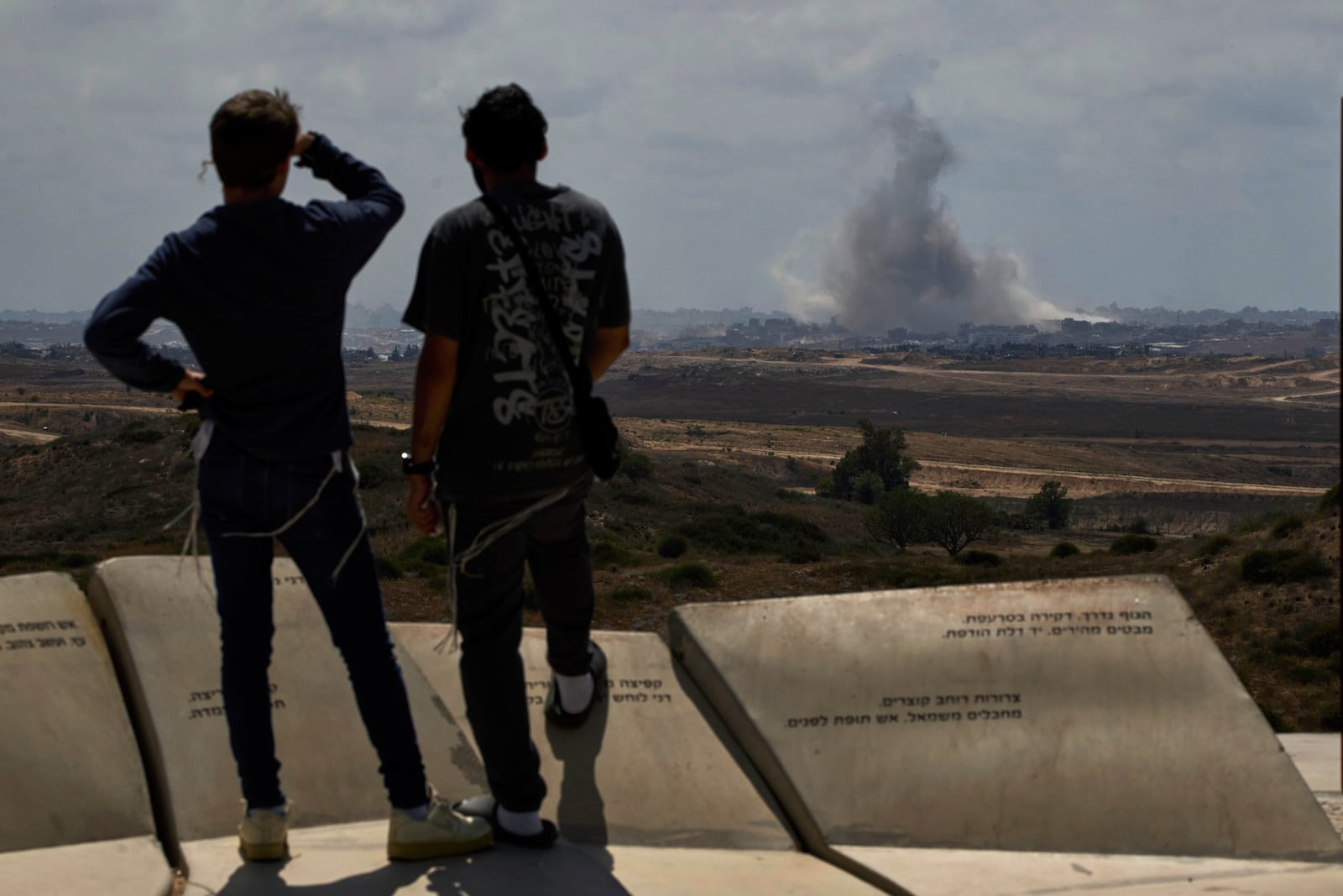 People watch smoke rising to the sky after an explosion in the Gaza Strip as they visit a sightseeing area in Sderot, southern Israel, Thursday, May 22, 2025. (AP Photo/Leo Correa)