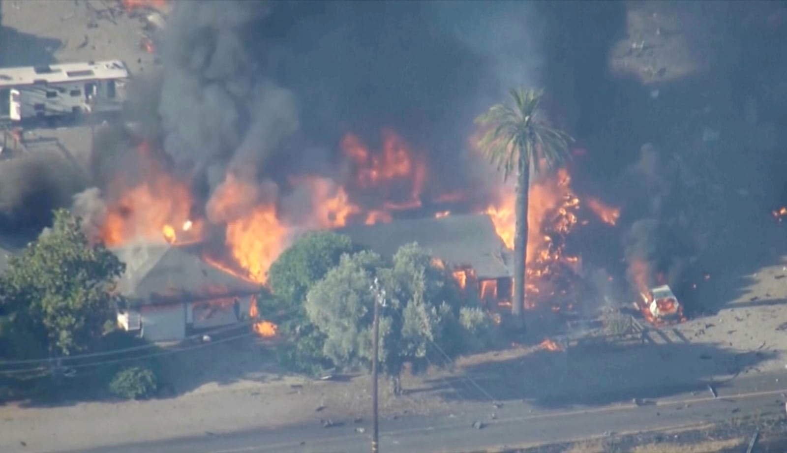 In this aerial image taken from video, smoke and flames rise from a fireworks warehouse explosion, July 1, 2025. (KGO via AP)