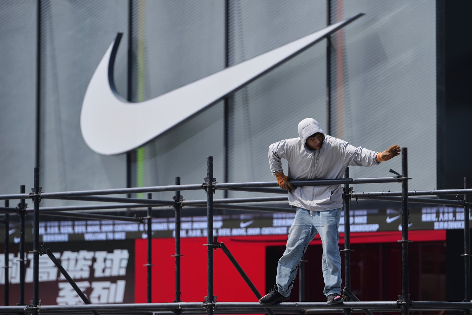 A worker installs a platform near a Nike store outside a shopping mall in Beijing, Sunday, May 11, 2025. (AP Photo/Andy Wong)