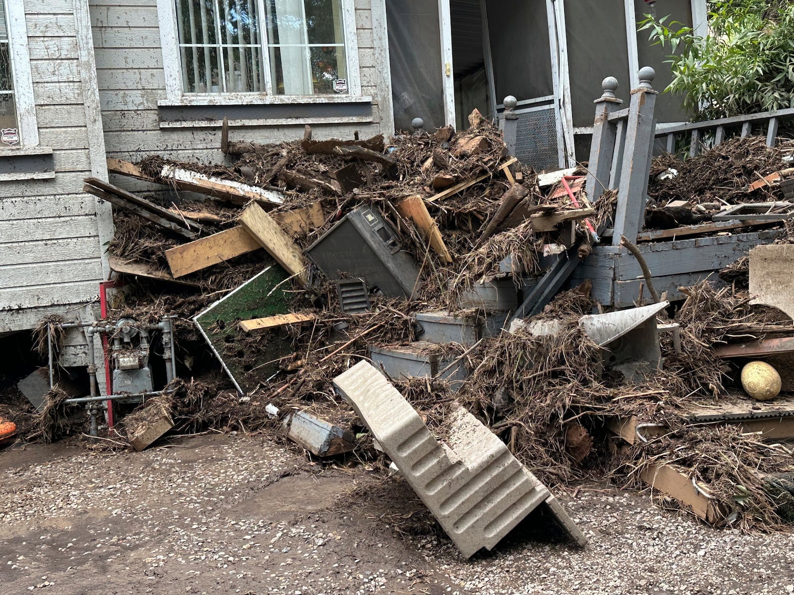 In this photo provided by Barbara Arthur, damage from flash flooding with mud and debris is seen outside a house at the Riverside RV Park, Wednesday, July 9, 2025, in Ruidoso, N.M. (Barbara Arthur via AP)