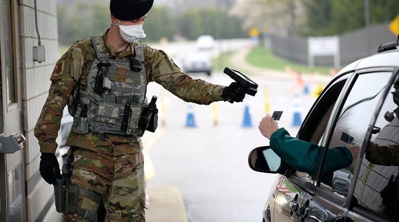Airman 1st Class Matthew Neimi of the 88th Security Forces Squadron scans the ID card of a retiree at Wright-Patterson Air Force Base last March. Under new Defense Department guidelines, masks and face coverings must be worn upon installation entry but lowered briefly for identification purposes. U.S. AIR FORCE PHOTO/TY GREENLEES