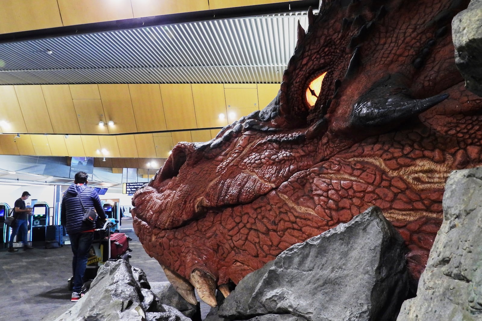 Passengers walk past a sculpture of the dragon Smaug from the Hobbit films at the check-in area at Wellington Airport in Wellington, New Zealand, Monday, May 5, 2025. (AP Photo/Charlotte Graham-McLay)