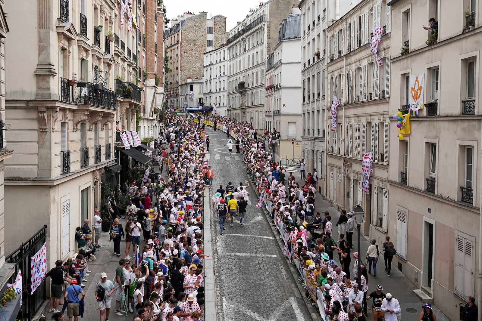 Cycling fans run on the street in the Montmartre district before the last stage of the Tour de France cycling race between Mantes-la-Ville and Paris, Sunday, July 27, 2025 in Paris (AP Photo/Laurent Cipriani)