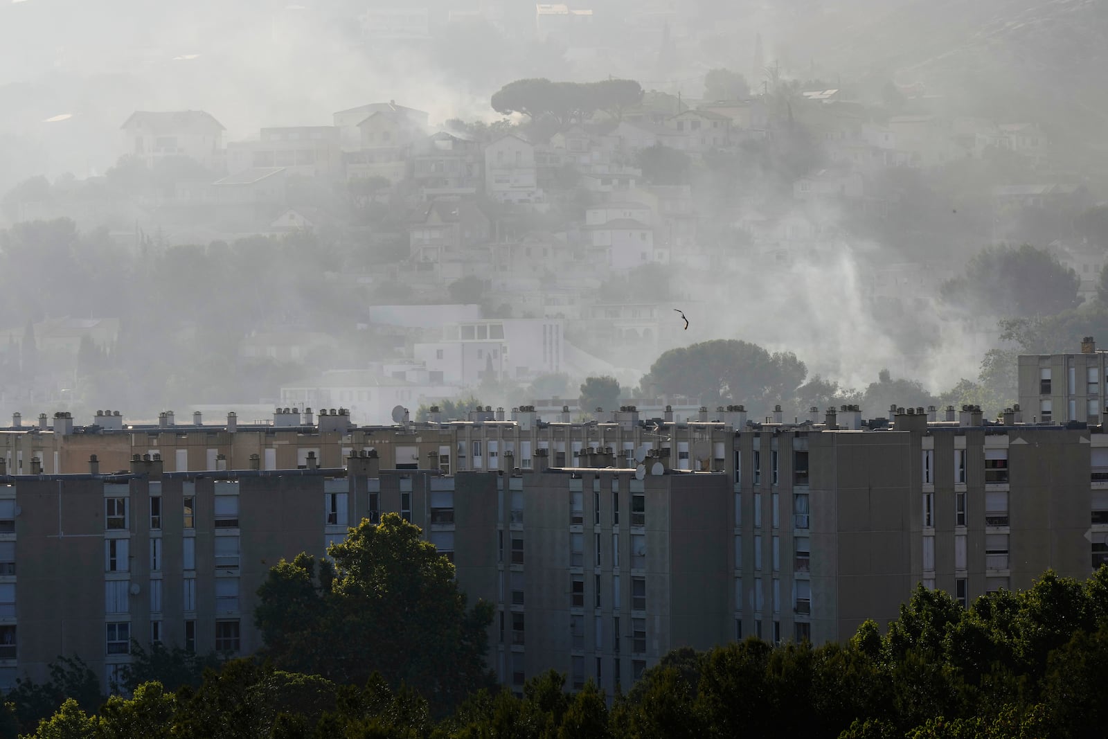 Smoke rises behind buildings during wildfire Tuesday, July 8, 2025 in La Catellane district of Marseille, southern France. (AP Photo/Lewis Joly)