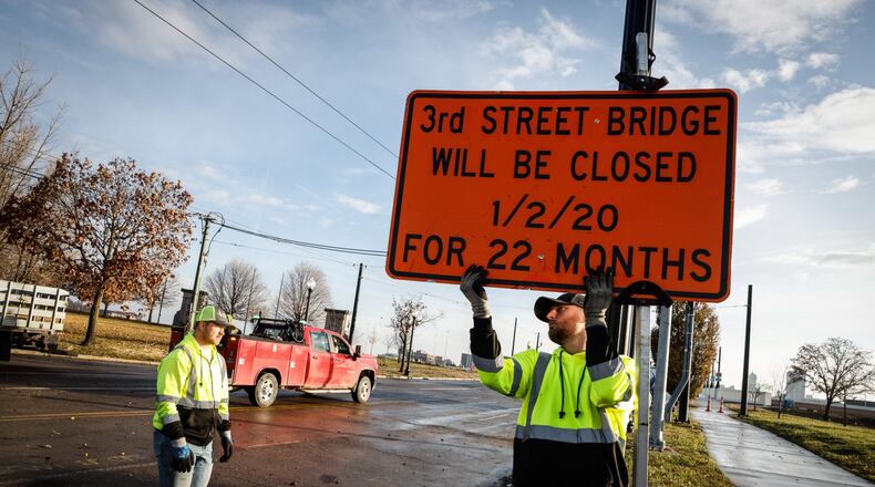 Kevin Kirk, left, and Wes Minton remove road closed signs from the newly rebuilt Third Street bridge in Dayton on Thursday Dec. 2, 2021. JIM NOELKER/STAFF