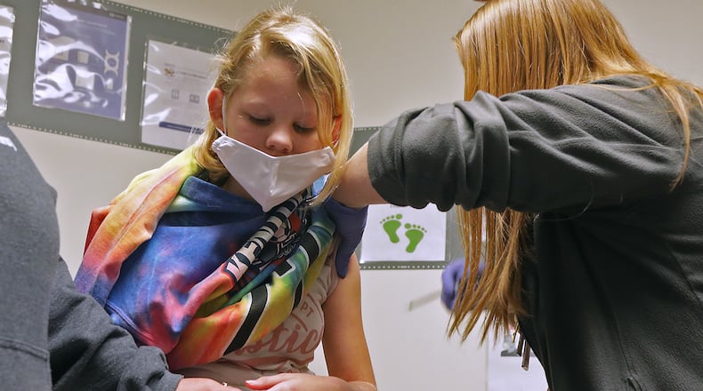 Clark and Champaign County school coronavirus cases dropped by over 70 during Thanksgiving break. Here, Hayley Chaney, 10, holds her mom's hand as she gets a COVID-19 vaccine shot at the Rocking Horse Center last month. BILL LACKEY/STAFF