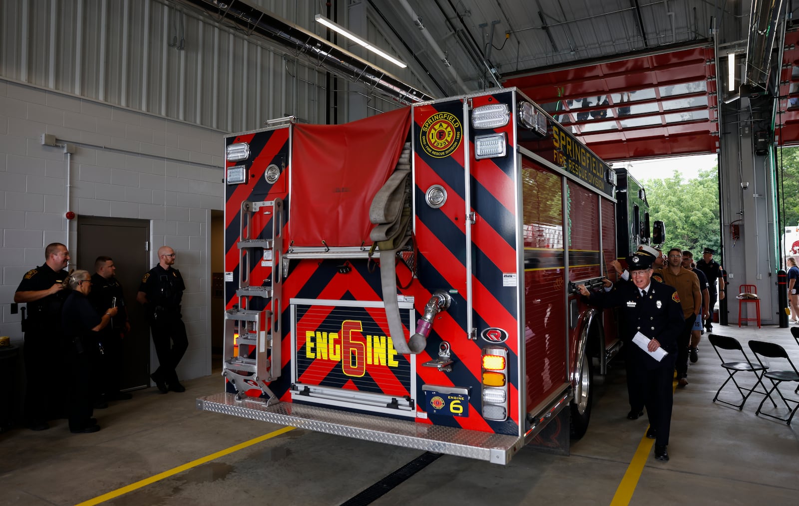 Chaplin Joe Kelly, front right, of the Springfield Fire Rescue Division, leads a group as they push a fire truck to symbolize the opening of Springfield Fire Station 6 on Tuesday, June 17, 2025, on South Charleston Pike. JOSEPH COOKE/STAFF