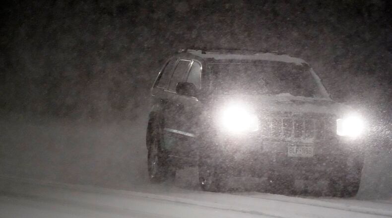 A motorist guides an SUV along a street as a heavy snowfall swept over the region Wednesday night, Feb. 24, 2021, in Denver. (AP Photo/David Zalubowski)