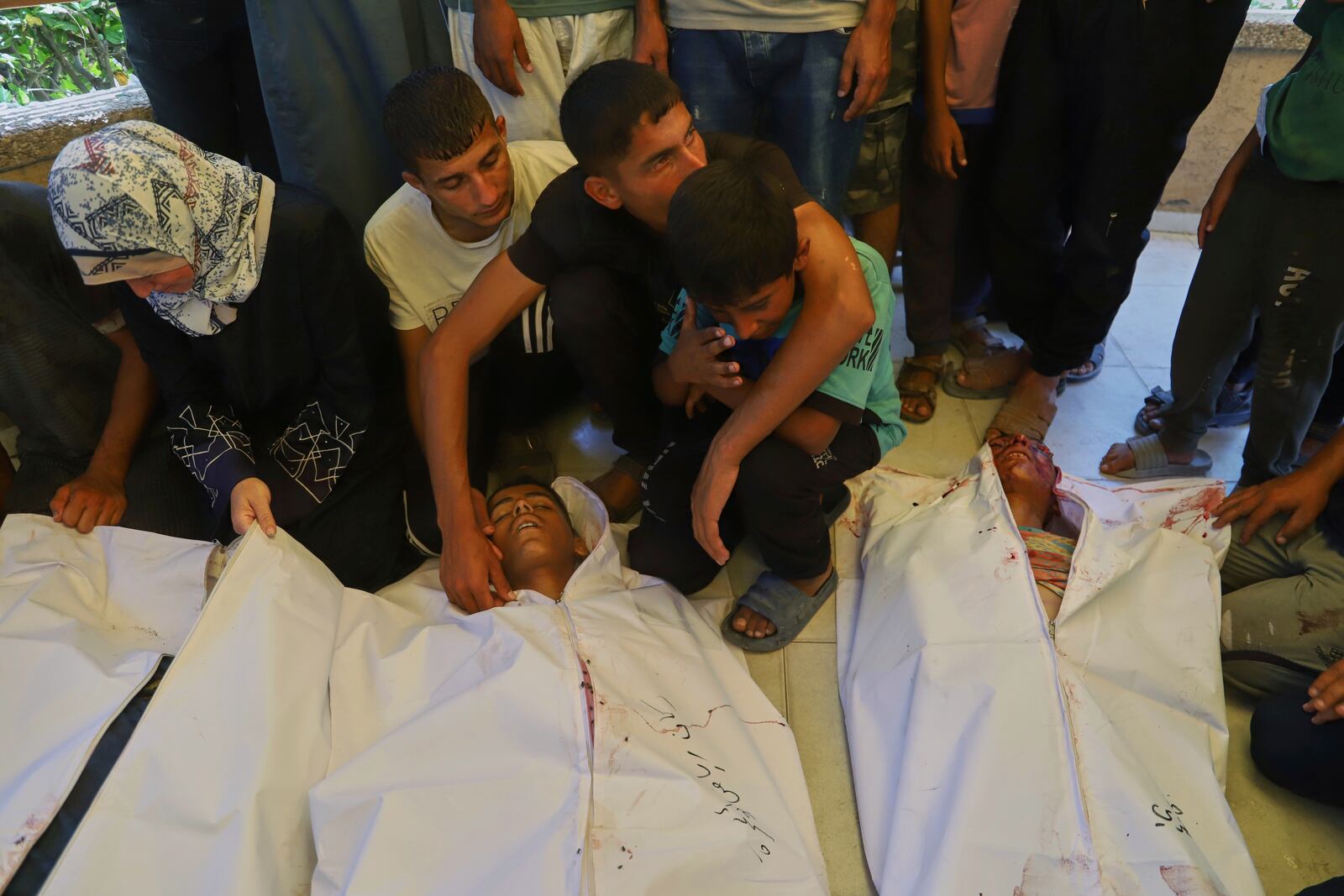 EDS NOTE: GRAPHIC CONTENT - Palestinians mourn over the bodies of people who were killed while returning from one of the Gaza Humanitarian Foundation distribution centers operated by the U.S.-backed organization, according to Nasser Hospital, during their funeral in Khan Younis, Monday, June 30, 2025. (AP Photo/Mariam Dagga)
