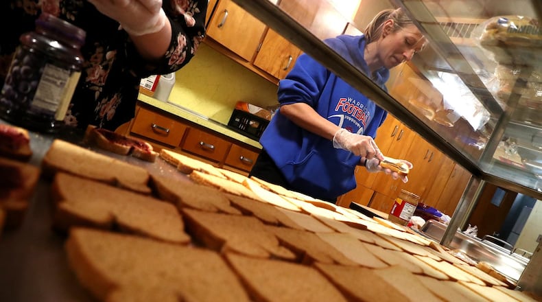 Erin Duke spreads the peanut butter for dozens of peanut butter and jelly sandwiches being assembled at H.O.P.E. Monday. H.O.P.E, a nonprofit organization, is providing students and families in need with lunch and dinner. BILL LACKEY/STAFF