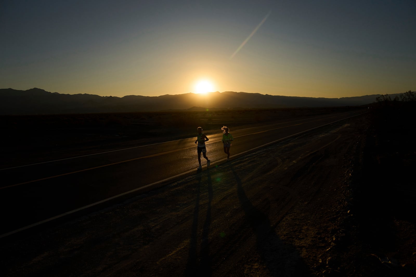Danny Westergaard, left, runs with pacing help from daughter Madison Westergaard as the sun rises during the Badwater 135 Ultramarathon, Tuesday, July 8, 2025, in Death Valley National Park, Calif. (AP Photo/John Locher)