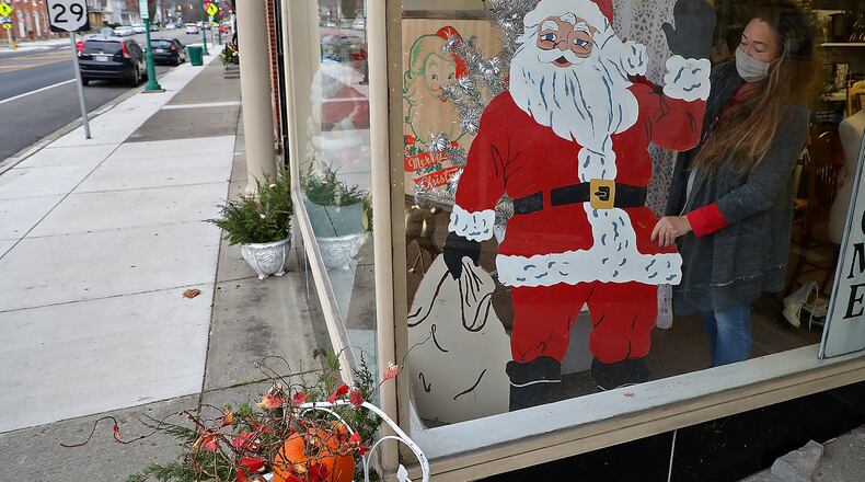 Tina Blakeman, owner of the Vintage Traveler antique store in downtown Urbana, decorates the front windows of her show for Christmas Tuesday. BILL LACKEY/STAFF