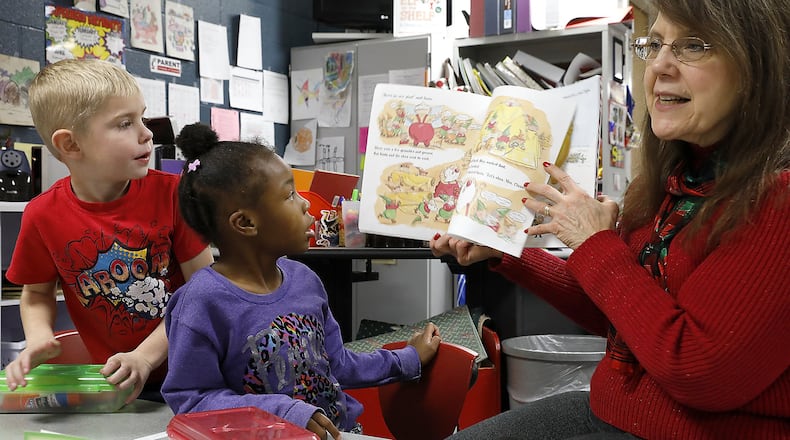 Liam Comley and Ja’Niyah Jones, students in Angie Caudill’s kindergarten class at Perrin Woods Elementery, follow along with tutor Jo Ann Cooper as she reads a story in class Thursday. Bill Lackey/Staff