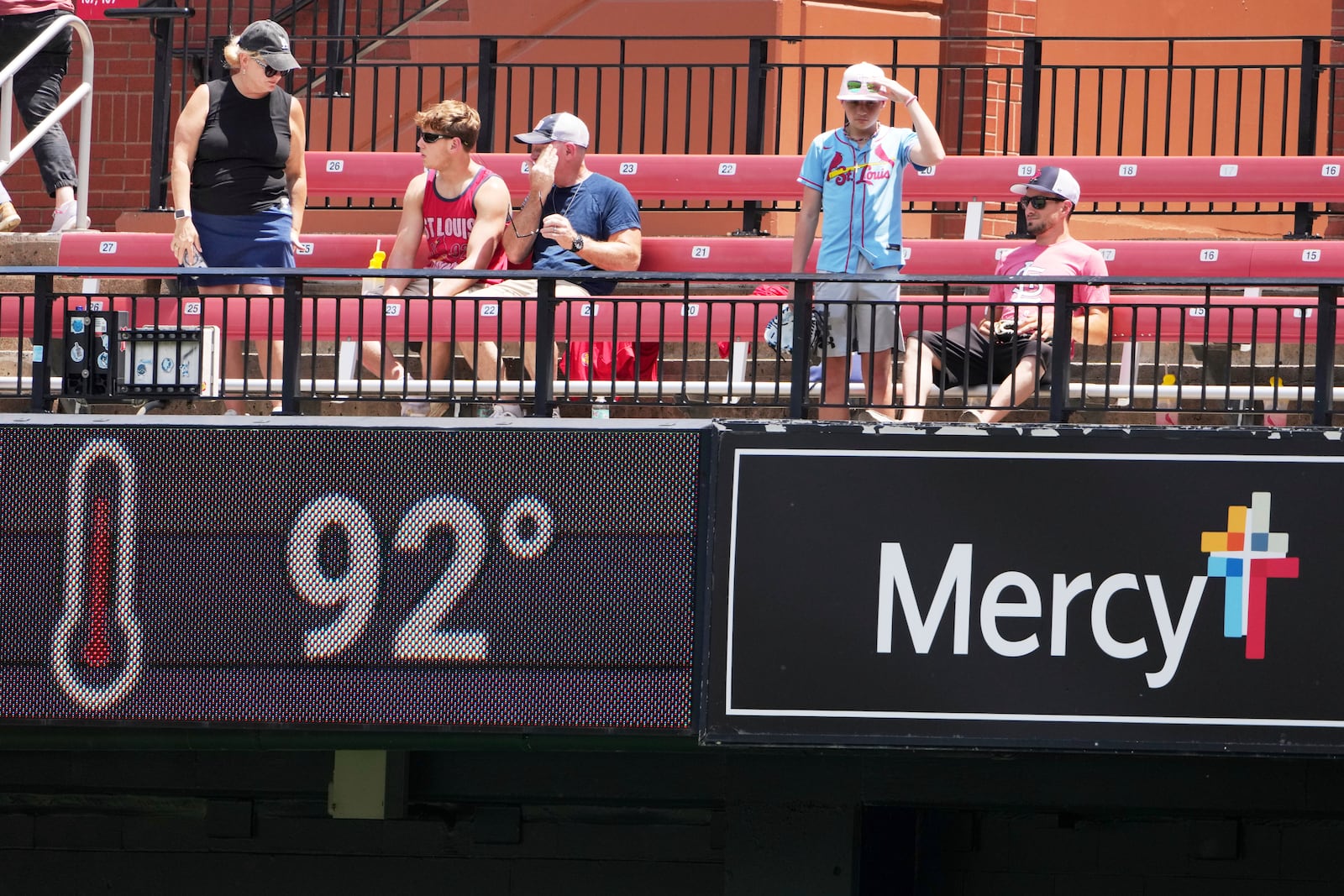 Fans in the bleachers try to stay cool in Busch Stadium before the start of a baseball game between the St. Louis Cardinals and the Cincinnati Reds Saturday, June 21, 2025, in St. Louis. (AP Photo/Jeff Roberson)