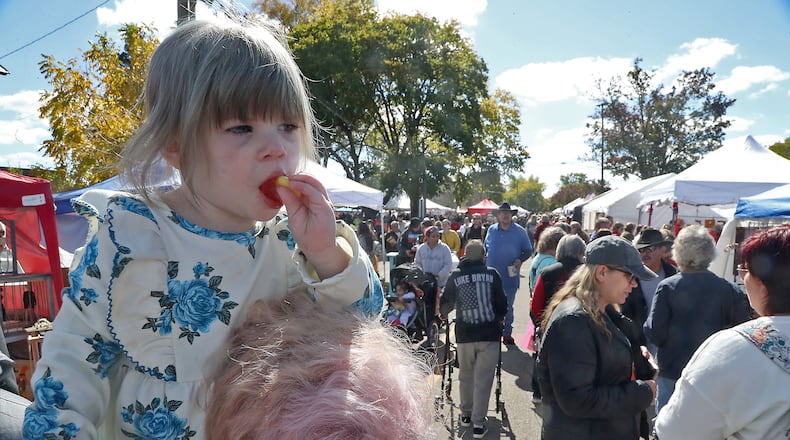 Paisley Norrod rides on the shoulders of her mother, Jae, as they make their way through the crowd Saturday, Oct. 8, 2022 at the Enon Apple Butter Festival. BILL LACKEY/STAFF