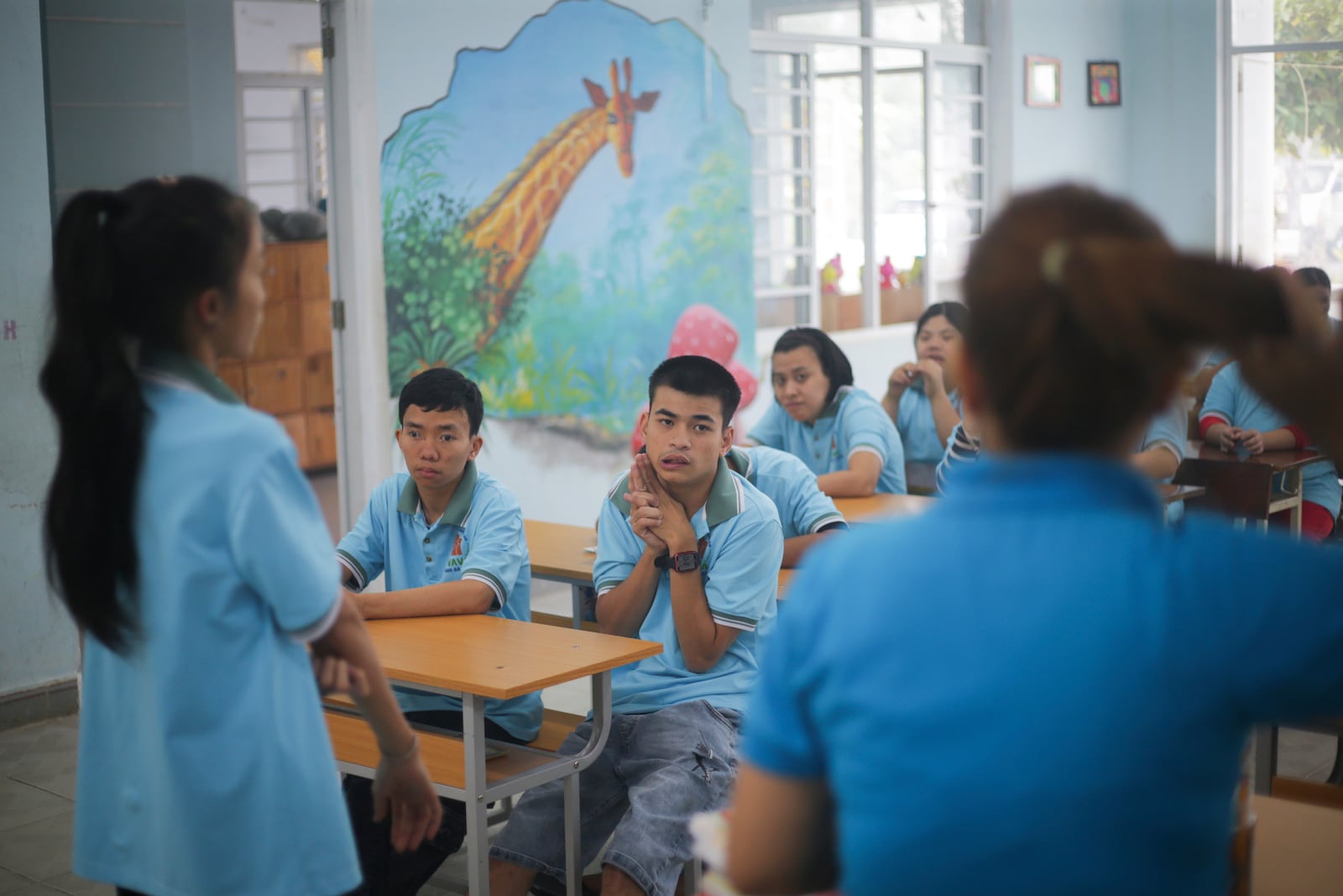 Truong Minh Phu, 20, centre, sits in a classroom with other students at a school for victims of Agent Orange in Da Nang, Vietnam, March 7, 2025. (AP Photo/Aniruddha Ghosal)