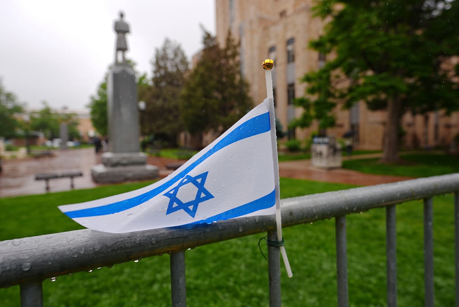 The flag of Israel tops a makeshift memorial for victims of an attack outside of the Boulder County, Colo., courthouse as a light rain falls Tuesday, June 3, 2025, in Boulder, Colo. (AP Photo/David Zalubowski)