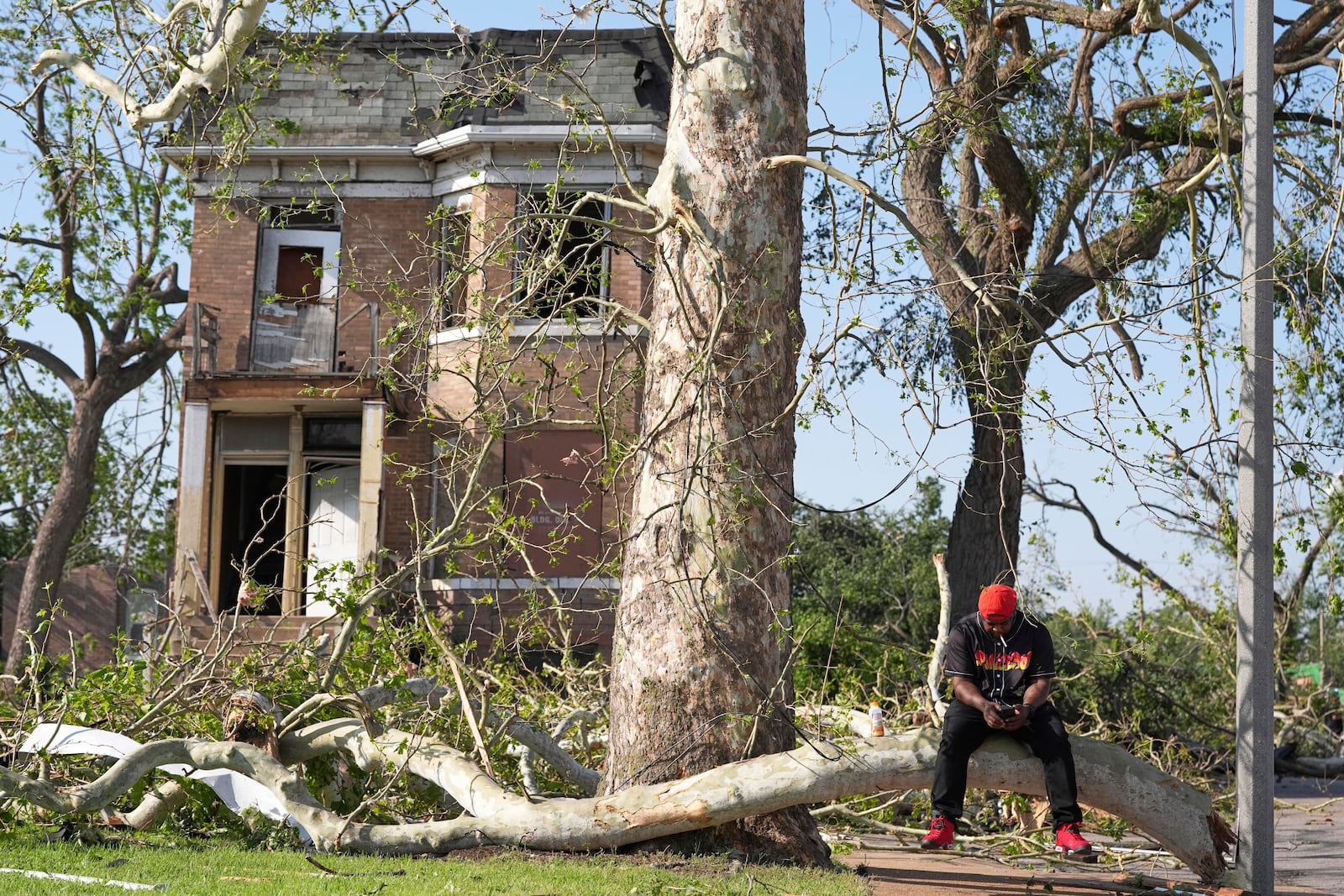 Steven Lampink sits on a downed tree after a severe storm moved through Friday, May 16, 2025, in St. Louis. (AP Photo/Jeff Roberson)