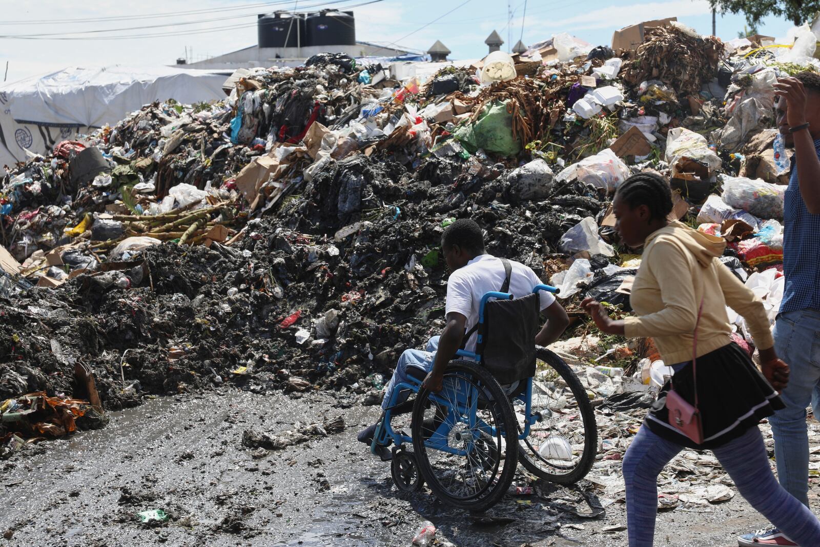 A man in a wheelchair tries to cross the street past garbage in the Petion-ville neighborhood of Port-au-Prince, Haiti, Friday, May 16, 2025. (AP Photo/Odelyn Joseph)