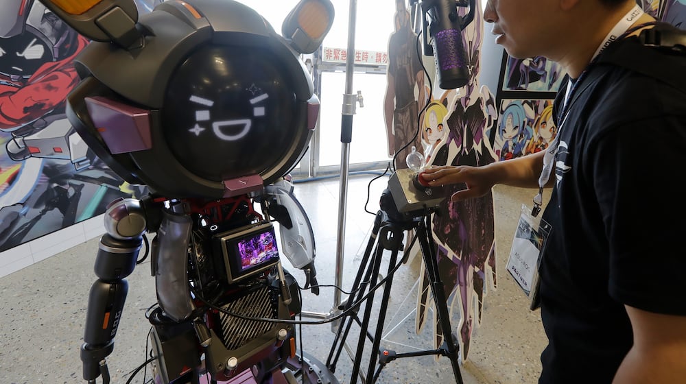 A man communicates with an ASUS Character Virtual Assistant, ROG Omni system during the AI EXPO in Taipei, Taiwan, Wednesday, March 25, 2026. (AP Photo/Chiang Ying-ying)