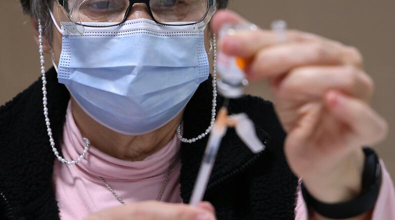 Weekly coronavirus cases continue to decline in Clark and Champaign county schools. Here, Peggy Smith gets a Moderna vaccine ready for someone at the Clark County Combined Health District's Vaccination Center last month. BILL LACKEY/STAFF