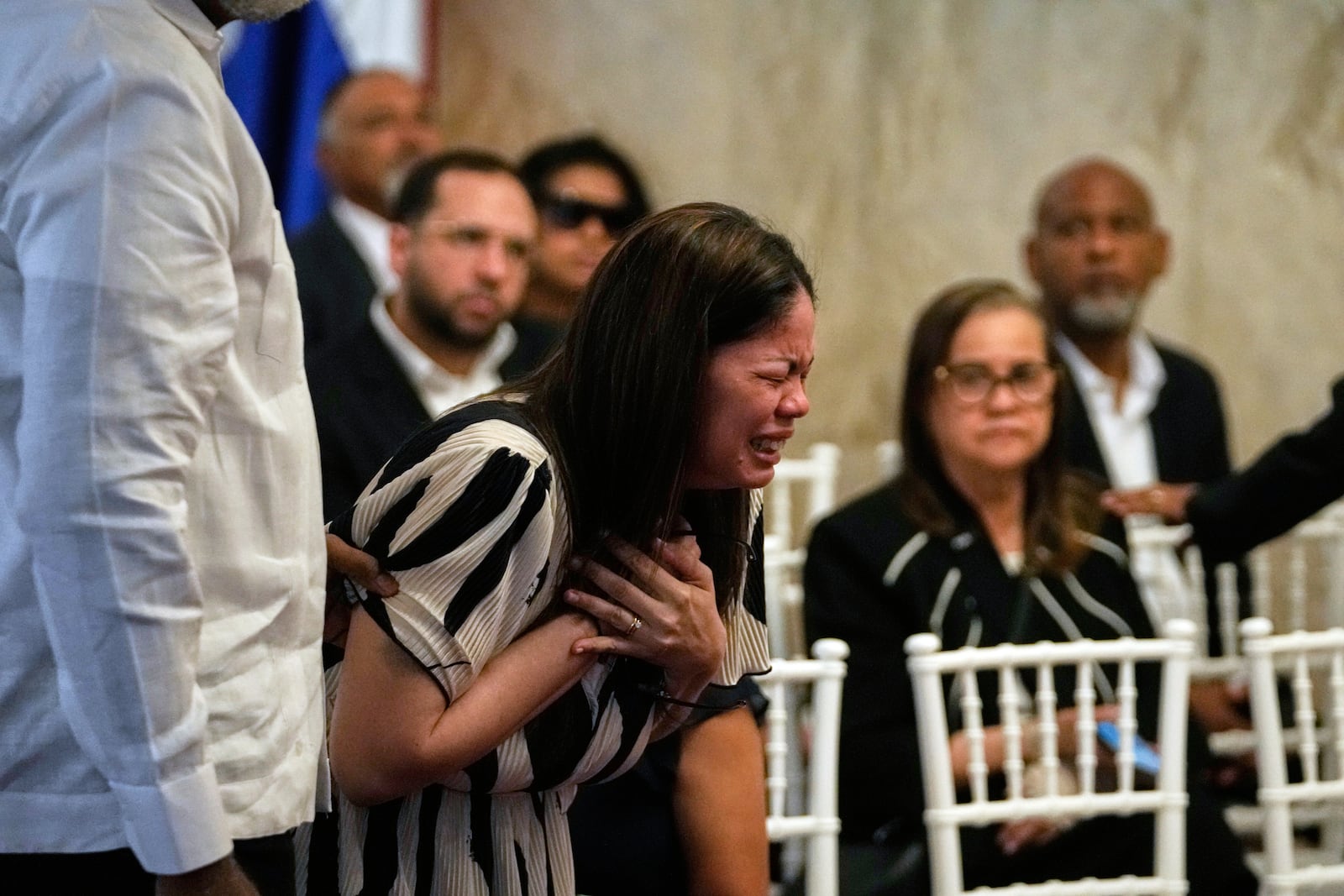 Zulinka, center, the daughter of Dominican singer Rubby Perez who died in the roof collapse at the Jet Set nightclub during his merengue concert, cries during his wake at the Eduardo Brito National Theater in Santo Domingo, Dominican Republic, Thursday, April 10, 2025. (AP Photo/Matias Delacroix)