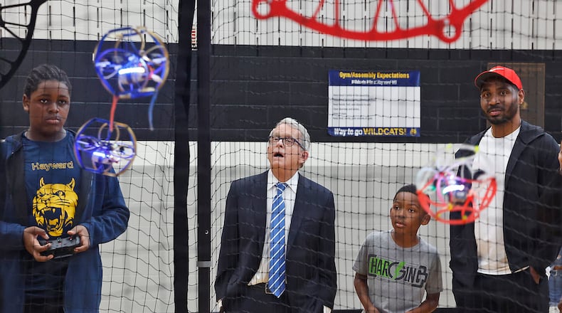 Gov. Mike DeWine and former Ohio State football star Braxton Miller watch as Jamir Rolls, a member of the Hayward Middle School drone soccer team, operates his drone Tuesday, May 7, 2024, in Springfield. The drone soccer team recently returned from Washington, D.C., where they competed in the National Drone Soccer Championships. Hayward was the first school in Ohio to have a drone soccer team. BILL LACKEY/STAFF