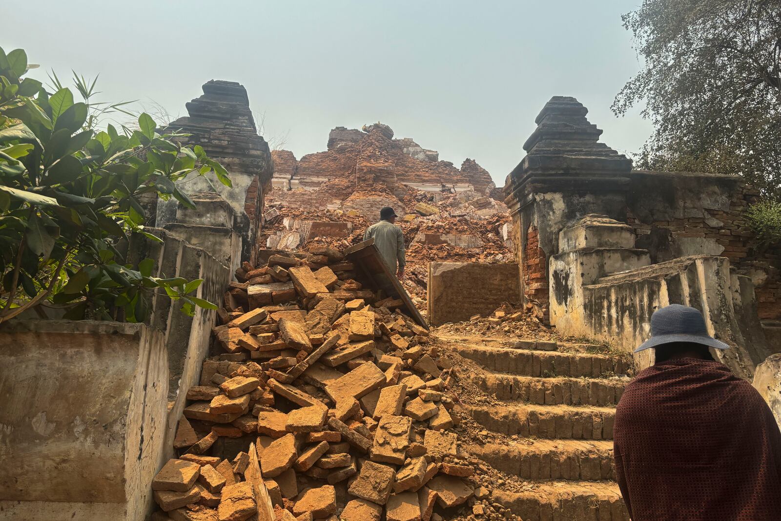 Visitors walk near damaged Maha Aungmye Bonzan Monastery, commonly known as the Me Nu Brick Monastery, in the aftermath of Friday's earthquake in Innwa, Tada-U township, Mandalay, Myanmar, Friday, April 4, 2025. (AP Photo)