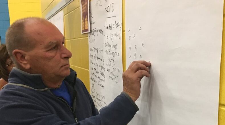 A Northeastern resident is shown putting one of his three stickers on option two during a school forum held two weeks ago. The option, to build two PreK-12 buildings, was the number one choice but those who attended the meeting.