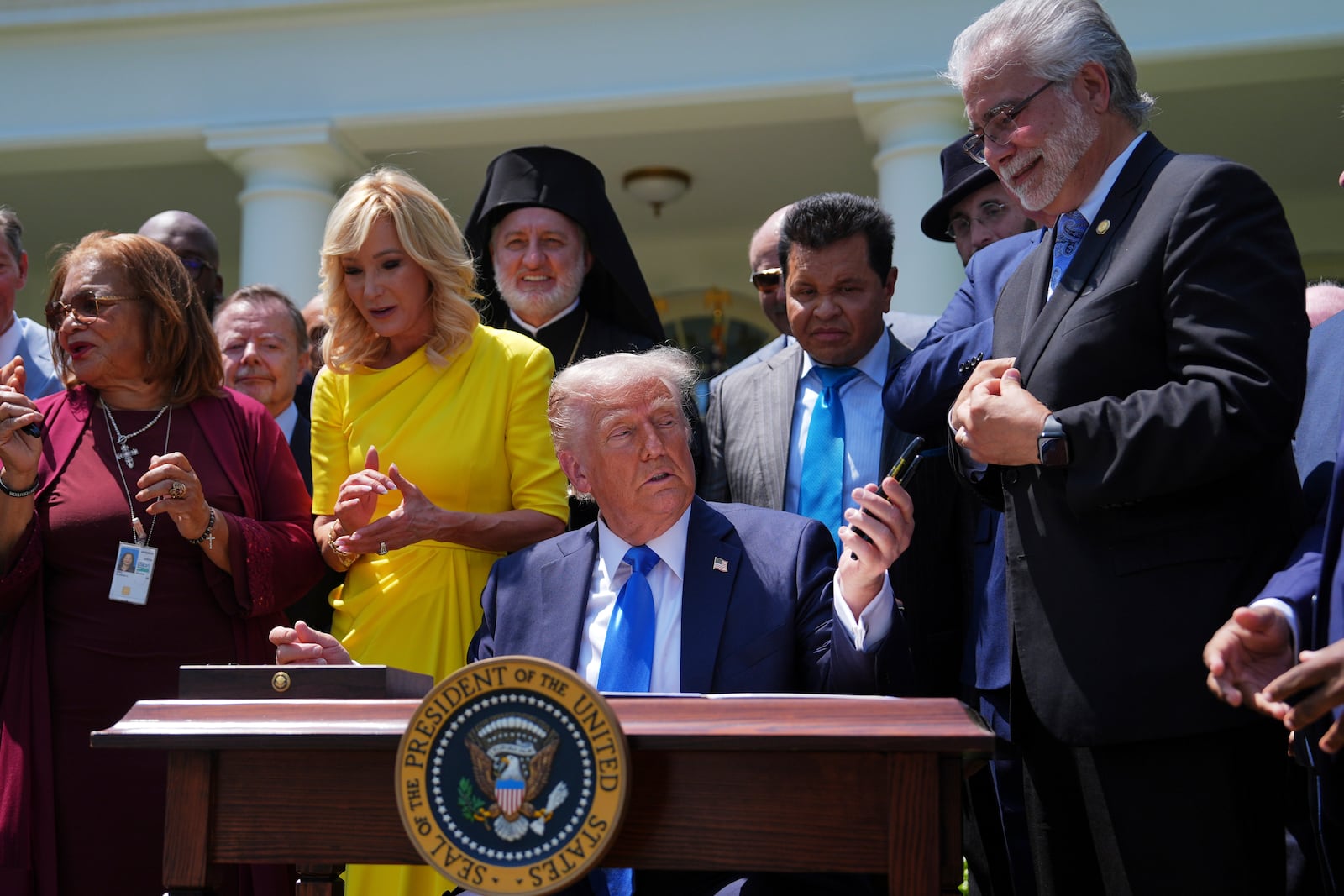 President Donald Trump hands pens used to sign an executive order establishing the Religious Liberty Commission, to religious leaders during a National Day of Prayer event in the Rose Garden of the White House, Thursday, May 1, 2025, in Washington. (AP Photo/Evan Vucci)