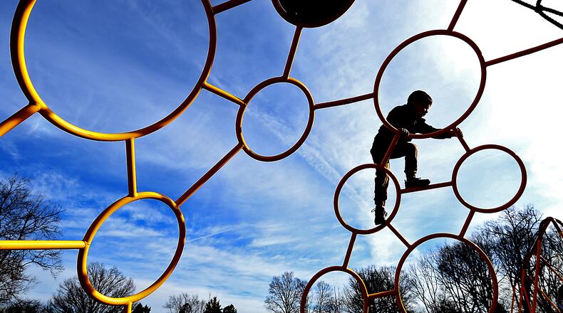 A child plays on the playground at Smith Park in New Carlisle Monday as he and his family take advantage of the unseasonably warm temperatures and sunshine. BILL LACKEY/STAFF