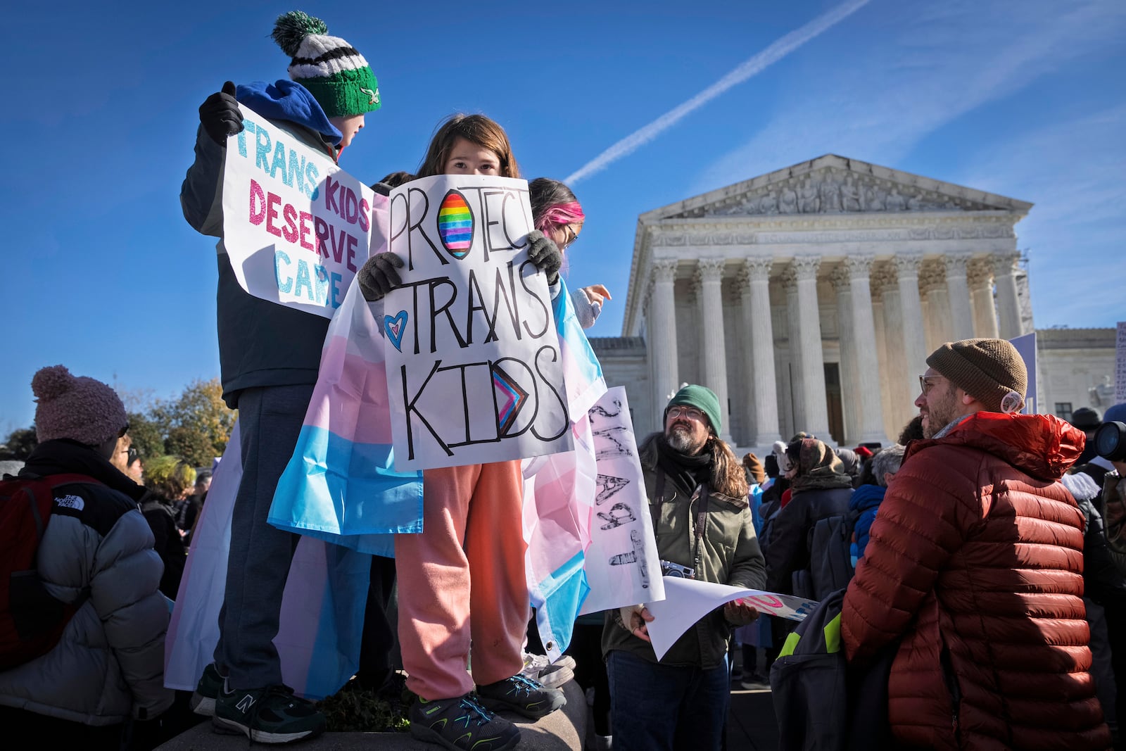 FILE - Children hold signs and transgender pride flags as supporters of transgender rights rally by the Supreme Court, Dec. 4, 2024, in Washington. (AP Photo/Jacquelyn Martin, File)