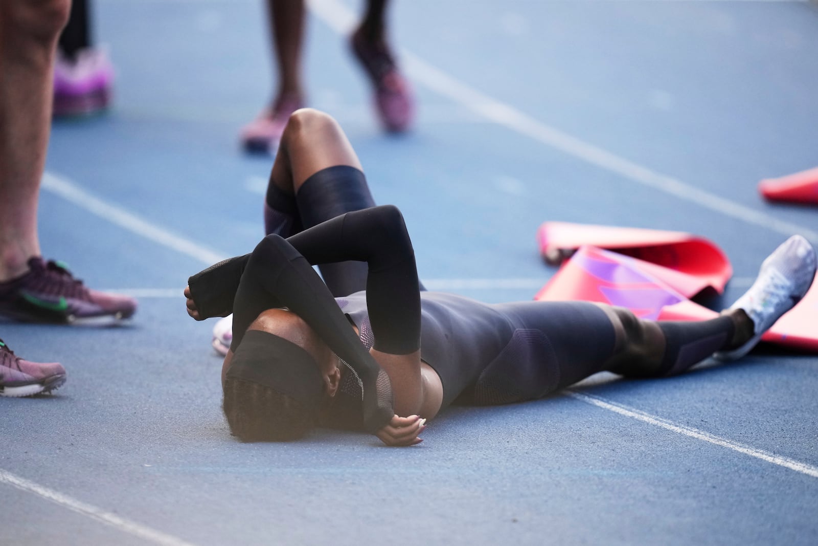 Faith Kipyegon, from Kenya, lies on the track after crossing the finish line in her attempt to become the first woman to run a mile in under four minutes, at Stade Charlety in Paris, Thursday, June 26, 2025. (AP Photo/Christophe Ena)