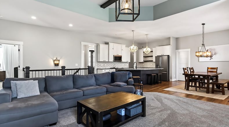 The open concept kitchen, dining room and great room are on the back of the house. There is LVP flooring in the kitchen and dining area and carpeting in the great room. There is a gas fireplace in the great room and an exterior door opening to the patio. CONTRIBUTED