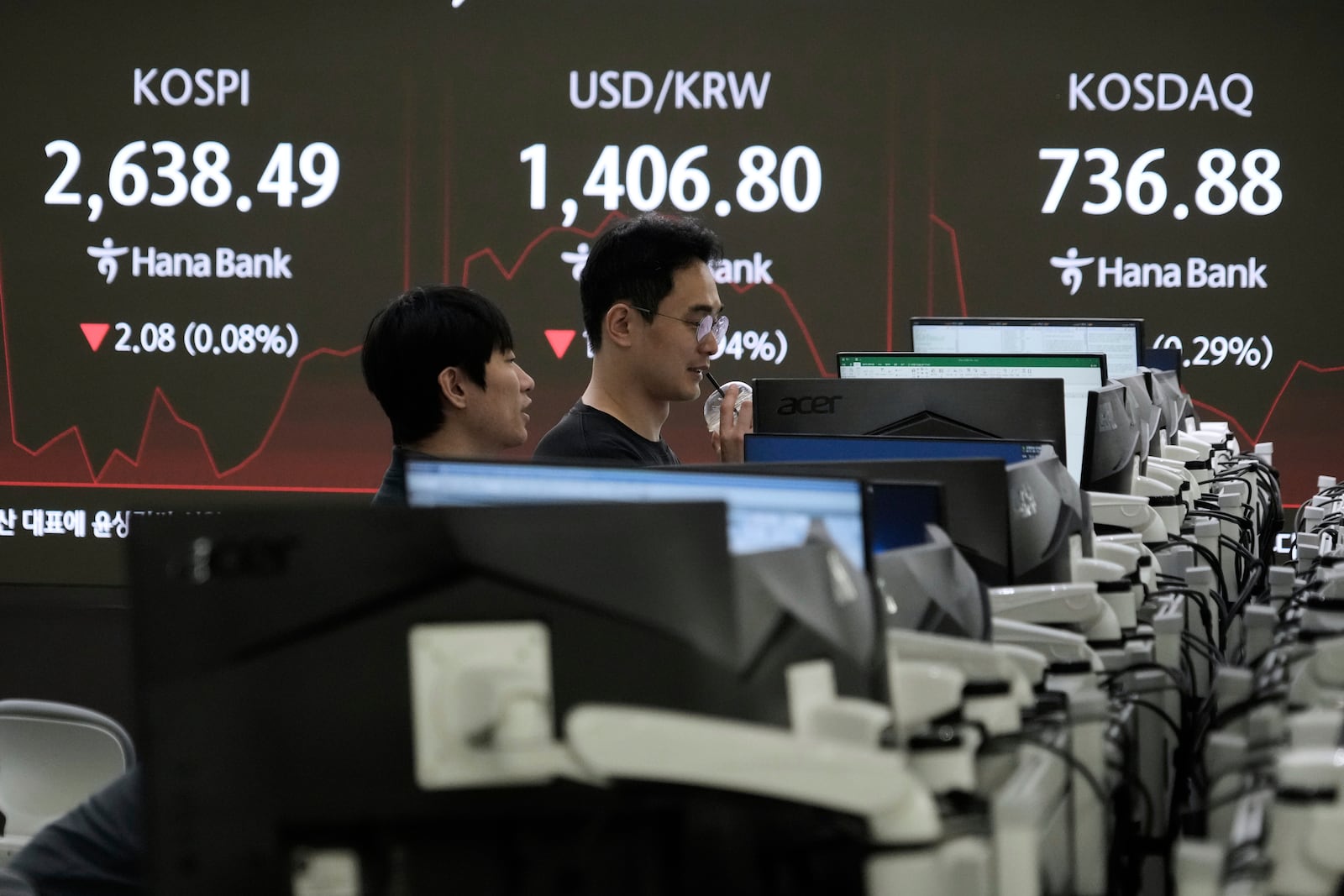 Currency traders watch monitors near a screen showing the Korea Composite Stock Price Index (KOSPI), top left, and the foreign exchange rate between U.S. dollar and South Korean won, top center, at the foreign exchange dealing room of the KEB Hana Bank headquarters in Seoul, South Korea, Thursday, May 15, 2025. (AP Photo/Ahn Young-joon)