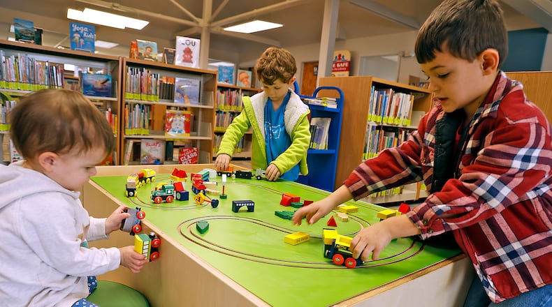P.J. Fields, left, and her brothers, Elliott, center, and Logan play with the trains in the newly renovated Youth Services Department at the New Carlisle Public Library Monday, Feb. 6, 2023. The library has spent the past few weeks working on the project, which includes replacing the furnature and frooring as well as a dedicated area for teens, an adaptable space for story time and other programs and a circulation desk in the Youth Services area. It is the library's first remodel in nearly 20 years. BILL LACKEY/STAFF