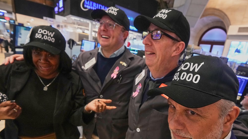 Trader Joel Lucchese, right, and colleagues wear "DOW 50,000" caps on the floor of the New York Stock Exchange as the Dow Jones industrial average intra-day number topped the 50,000 level for the first time, Friday, Feb. 6, 2026. (AP Photo/Richard Drew)