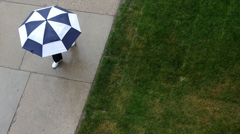 A woman walks along Columbia Avenue with an umbrella Wednesday during a rain shower. BILL LACKEY/STAFF