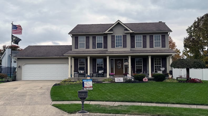 The front of the home has a full covered porch and a concrete driveway leading to a two-car attached garage.