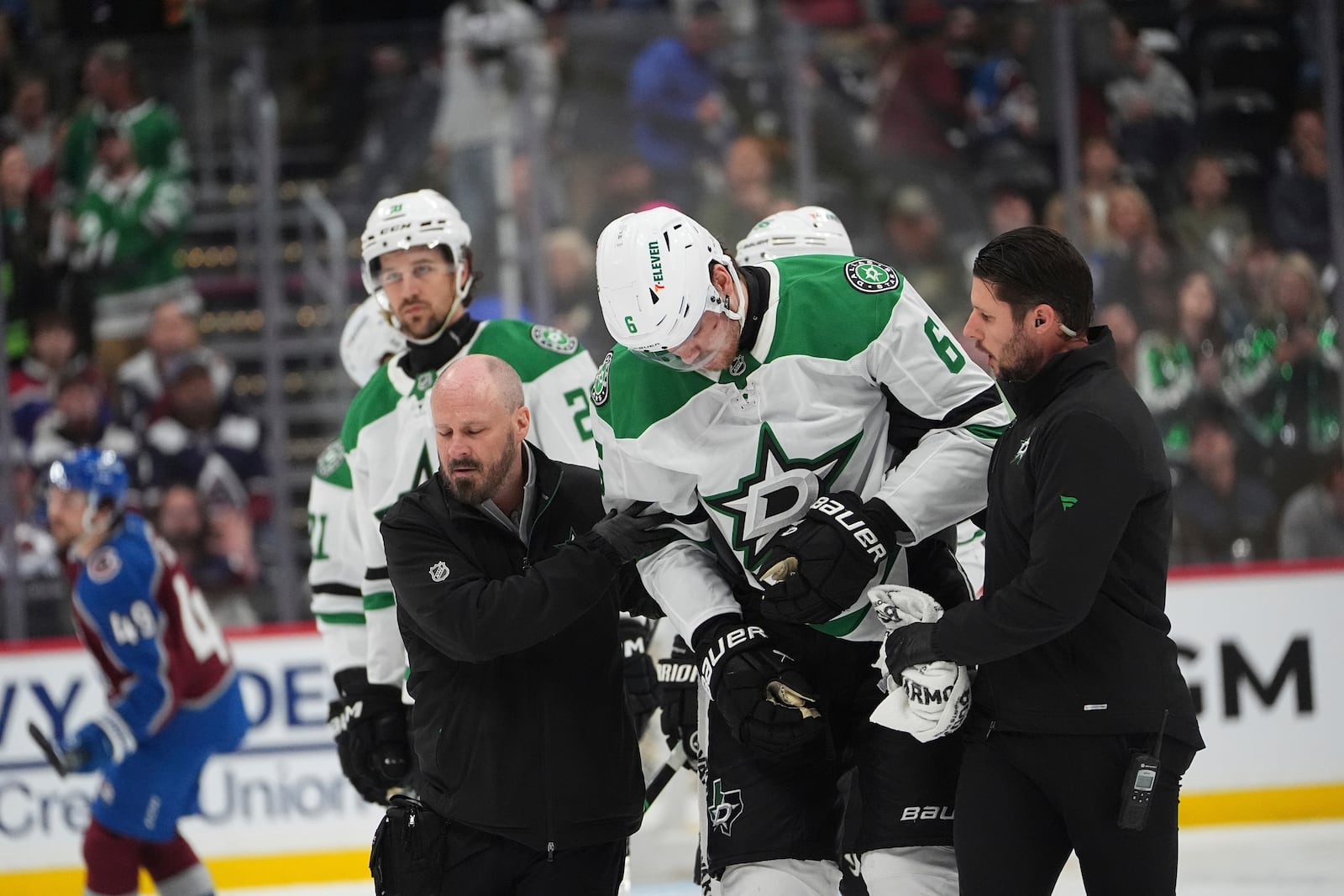 Dallas Stars defenseman Lian Bichsel, center, is helped off the ice by trainers after being injured in the second period of Game 6 of an NHL hockey first-round playoff series against the Colorado Avalanche, Thursday, May 1, 2025, in Denver. (AP Photo/David Zalubowski)