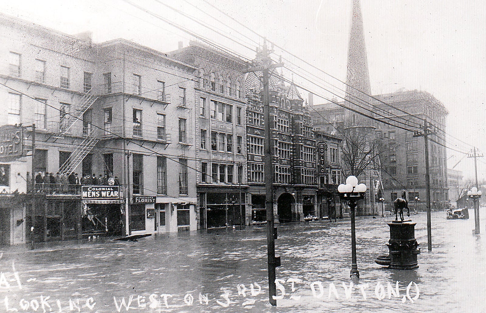 Third Street in downtown Dayton during the Great Dayton Flood of 1913. At the time the street featured a hotel, a menswear store, a florist and the Arcade building (just before the "bowling" sign in the photo) among other buildings.