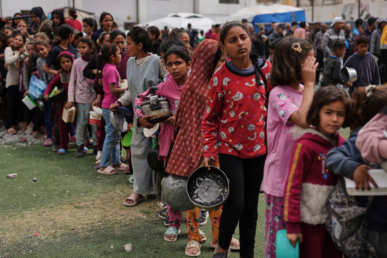 Palestinian children line up to wait for donated food at a distribution center in Nuseirat, central Gaza Strip, Friday, April 11, 2025. (AP Photo/Abdel Kareem Hana)